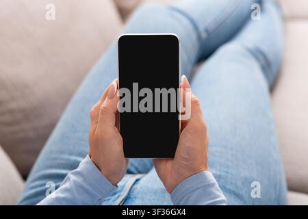 Workflow-Management und Ansicht von Online-Schulungen. Frau liegt auf dem Sofa und hält Smartphone Stockfoto