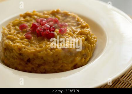 Nahaufnahme von cremigem Kürbisrisotto, garniert mit frischen Granatapfelsamen Stockfoto