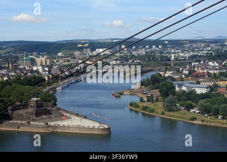 Blick hinab vom Hügel über die Seilbahn mit Blick auf das Deutsche Eck in Koblenz mit dem Rhein und Kreuzfahrtschiffen in der Ferne. Stockfoto