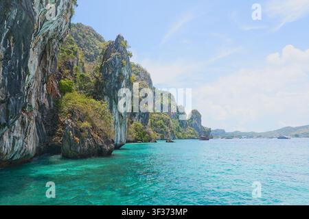 Dramatische Kalksteinklippe über kristallklarem türkisfarbenem Meer auf einer tropischen Inselparadies. Stockfoto