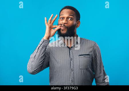 Lustige afrikaner Mann macht Zpping Lippen Geste mit der Hand Stockfoto