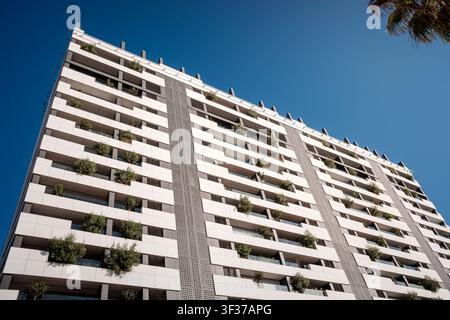Hochhaus-Wohnarchitektur mit bepflanzten Balkonen unter klarem Himmel Stockfoto