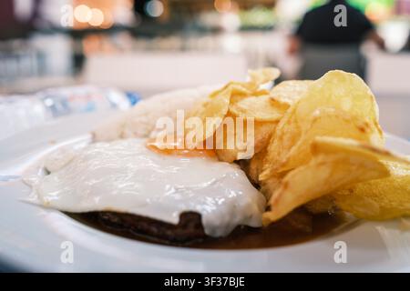 Hawaiianisches Loco-Moco-Gericht, das einen Burger, ein gebratenes Ei, Sauce, Reis und Kartoffelchips serviert Stockfoto