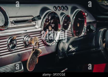 Nahaufnahme eines Vintage-Autodashboards mit chromen analogen Messgeräten und Schlüsseln im Zündschloss. Stockfoto