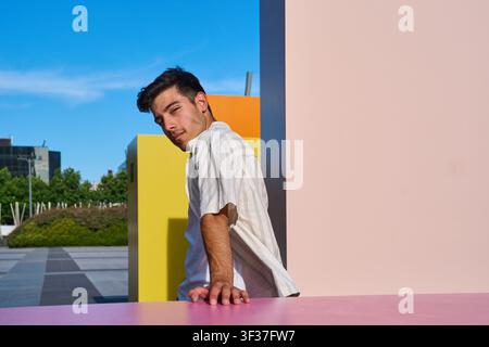 Junger Mann steht in einem Stadtpark mit bunten abstrakten Wänden und schafft ein lebendiges und modernes Bild Stockfoto