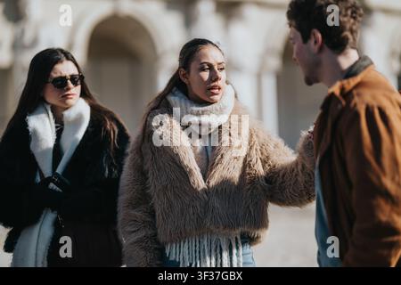 Freunde in einem angespannten Gespräch im Freien, während sie Wintermäntel in einer städtischen Umgebung tragen Stockfoto
