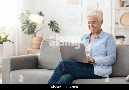Entspannen und Arbeiten zu Hause. Senior-Businessfrau sitzt mit Laptop auf der Couch Stockfoto