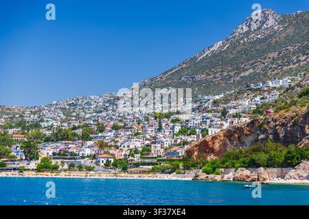 Kalkan Küstenstadt, die auf einem sonnigen Hügel mit weißen Häusern, einem Sandstrand, türkisfarbenem Wasser und kleinen Booten erbaut ist, erinnert an Sommerurlaub, Meeresluft Stockfoto