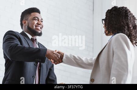 Afroamerikanische Geschäftspartner, die im Büro die Hände schütteln und sich einigen Stockfoto