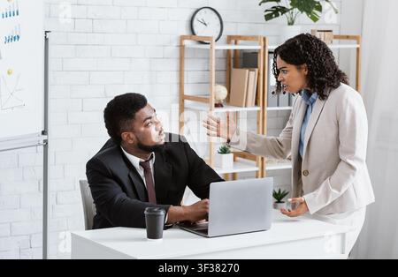 Wütend afroamerikanische Dame Chef schimpfen männlichen Mitarbeiter für Fehler in dringenden Projekt im Büro. Stresskonzept am Arbeitsplatz Stockfoto
