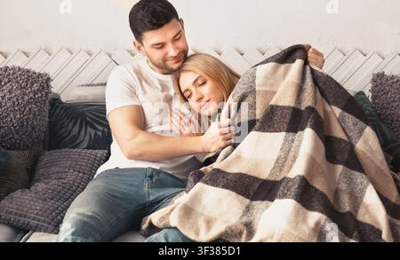 Paar, das sich unter einer Decke auf dem Sofa umarmt und entspannt, Wohnkonzept Stockfoto