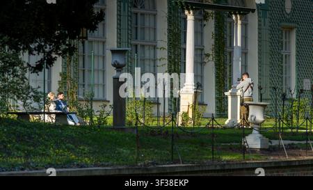 Fotograf fängt eine Outdoor-Porträt-Session eines jungen Paares nahe dem historischen Palast im Schlosspark während des frühen Frühlings in Łańcut, Polen Stockfoto