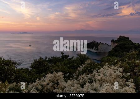 Ionisches Meer und weiße Klippen bei Kap Drastis, Korfu, Griechenland, die die warmen Farben eines sommerlichen Sonnenuntergangshimmels empfangen Stockfoto