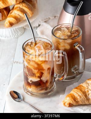 Zwei Gläser frisch eingeschenkter Eiskaffee vor einem hellen Hintergrund. Stockfoto