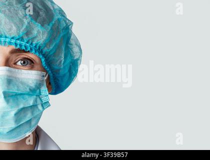 Halbes Gesicht einer Ärztin in Schutzmaske und Hut Stockfoto