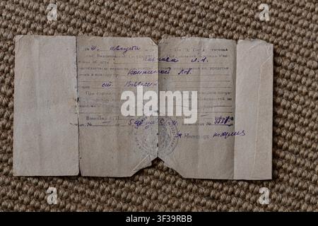 Altes sowjetisches Papier und historisches Dokument mit handgeschriebenem Text in blauer Tinte, einem runden Stempel, offiziellen Markierungen und Inschriften auf Russisch. Stockfoto