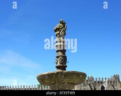 Dekorative Fontäne mit Santa-Bárbara-Statue in einem von Blumen übersäten mittelalterlichen Garten von Braga, Portugal Stockfoto