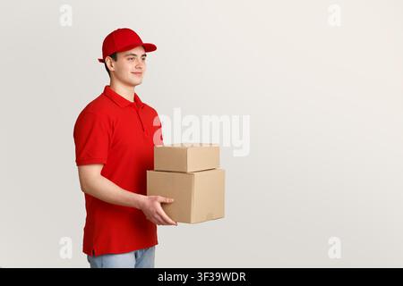 Online-Bestellung und Kurier. Liefermann in roter Uniform hält Kisten in Händen Stockfoto