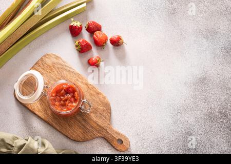 Hausgemachte Erdbeer-Rhabarber-Marmelade in offenem Gläser auf Holzbrett flach hingelegt Stockfoto