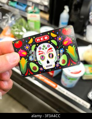 PLANO, TX, 2026 - 12. JULI 2026: Eine Person hält eine HEB-Giftkarte mit einem lebhaften Tag-der-Toten-Schädeldesign, verziert mit Avocados und Blumen Stockfoto