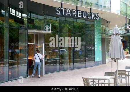 DALLAS, TX, USA - 13. JULI 2026: Ein Kunde betritt einen Starbucks-Laden, der durch eine Glasfassade und auffällige Beschilderung gekennzeichnet ist. Starbucks ist ein globaler Kaffeeritter Stockfoto