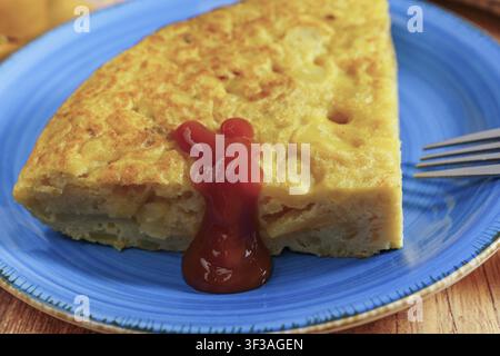 Spanische Kartoffelomelette - Tortilla de patatas - mit Ketchup überzogen, serviert als traditionelle Tapa oder lockeres Essen Stockfoto