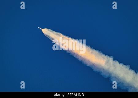 Artemis II hebt sich in einer brillanten Triebwerksdüse durch den Himmel, seine Raketenflamme lodert, während das Space Launch System zum Mond fliegt. Stockfoto
