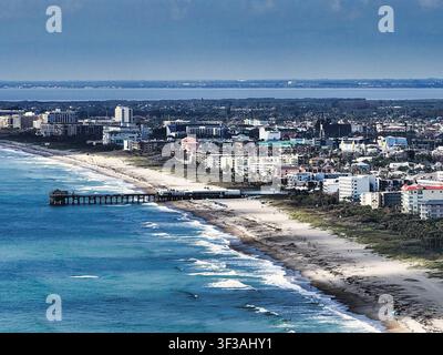 Luftbild vom Atlantischen Ozean aus von Cocoa Beach und seinem ikonischen Pier, der sich in die blauen Gewässer erstreckt, und fängt Floridas lebendige Küste und Surfsce ein Stockfoto