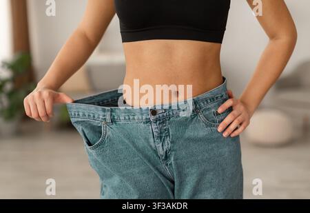Afrikanische Frau Trägt Alte Große Jeans Nach Dem Abnehmen Innen, Abgeschnitten Stockfoto
