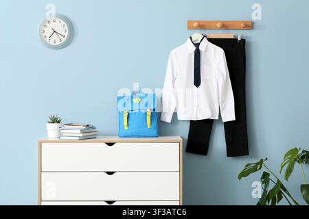Schuluniform und Rucksack eines Kindes hängen an der Wand Stockfoto