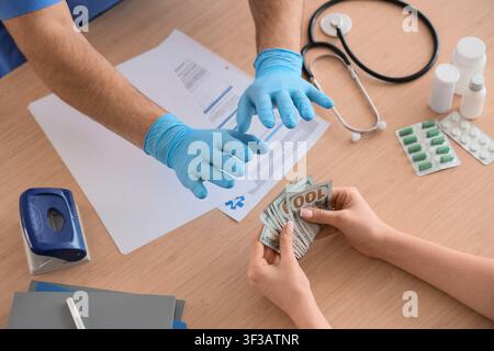 Hände, die Geld über medizinische Unterlagen und Ausrüstung tauschen Stockfoto