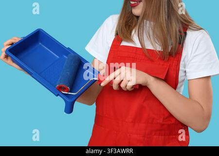 Malerin mit Malerwalze und Tablett auf blauem Hintergrund Stockfoto