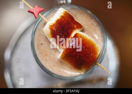 Marshmallows auf einem Stock in einem Getränk Stockfoto
