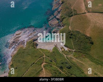 Luftbild vom Lansallos-Strand, einer abgeschiedenen Bucht an der Südküste von Cornwall, England. Umgeben von schroffen Klippen und grüner Landschaft. Stockfoto