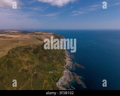 Eine Drohnenperspektive aus der Luft fängt die schroffen Küstenklippen und das tiefblaue Meer ein, das sich östlich von Lansallos Beach erstreckt. Stockfoto