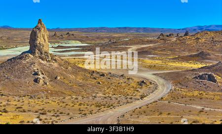 Trona Pinnacles Tufa Spire Windender Schotterweg und Wüsten-Hinterland Kalifornien Stockfoto