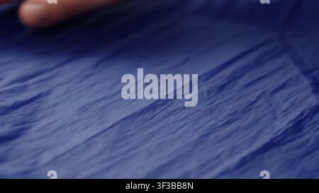 Männerhand prüft blauen Kunststofftaschenstoff Stockfoto