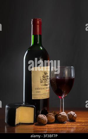Komposition mit Rotweinflasche, Weinglas, Walnüssen und Käse Stockfoto