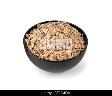 Dinkelflocken häufen sich in einer schwarzen Schüssel isoliert, trockene rohe geflachte Haferkörner, Weizen, Hafermehl oder Kleie, Gerste-Roggen-Getreide für Müsli oder Granola isoliert auf Stockfoto