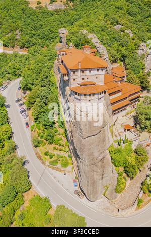 Hohe Luftaufnahme des Heiligen Klosters des Heiligen Nikolaus Anapausas, das auf einer steilen Klippenkuppe mit einer kurvenreichen Straße in Meteora Kalambaka Griechenland Europa erbaut wurde Stockfoto