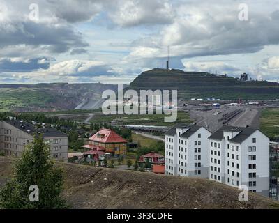 Blick auf Kiruna, Schweden, zeigt den Eisenerzbergbau, die städtische Landschaft und das terrassierte Bergbaugebiet unter einem bewölkten Himmel. Stockfoto