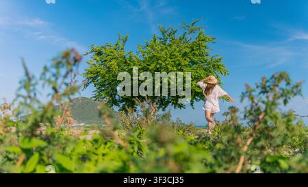 Frau, die ihren Hut unter einem Baum am Ufer anpasst Stockfoto