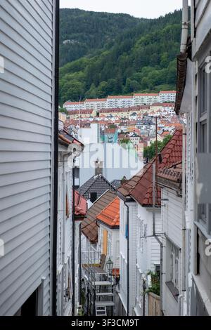 Charmaler Gassenweg in Bergen eingerahmt von weißen Holzhäusern mit Terrazzofassaden und einem bewaldeten Hügel, ideal für Reise- und redaktionelle Nutzung. Stockfoto
