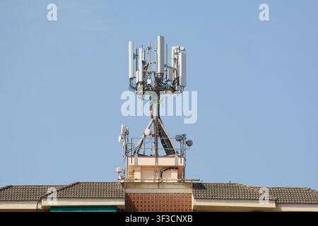 Viladecans, Spanien – 23. Juli 2026: Detaillierte Ansicht von Mobilfunkmasten und Kommunikationsgeräten, die auf dem Dach eines Gebäudes montiert sind. Stockfoto