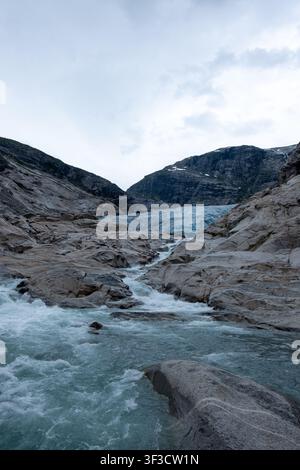 Gletscherschmelzwasser stürzt über polierte Felsen unter dem Nigardsbreen-Gletscher in Norwegen, ideal für Klimathemen und Naturkonzepte. Stockfoto