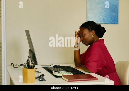 Schwarze Frau erlebt Arbeitsstress, während sie am Bürotisch sitzt Stockfoto