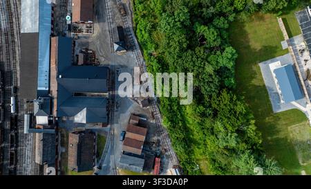 Ein altes Industriegebiet neben einem Grünraum in einer Stadt. Das Bild zeigt Gebäude und ein Waldgebiet. In der Nähe gibt es ein offenes Feld und einige sichtbare Strukturen. Stockfoto