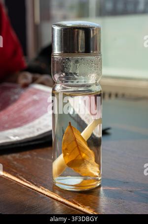 Essig mit Gewürzen in einer Glasflasche auf einer Restauranttheke, ein asiatisches Dressing für Fleischgerichte Stockfoto