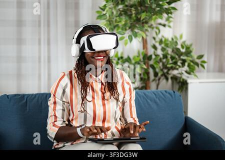 Frau erkundet das virtuelle Realität-Metauniversum mit Headset und Tablet Stockfoto