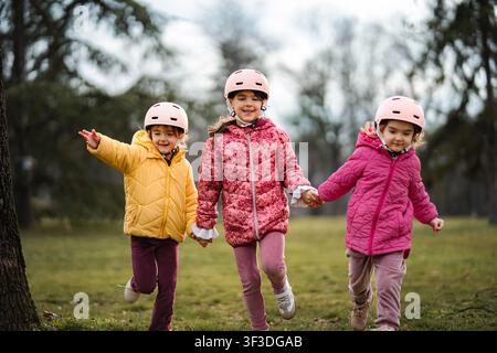 Drei glückliche Kinder mit Helmen, die im Park spielen Stockfoto